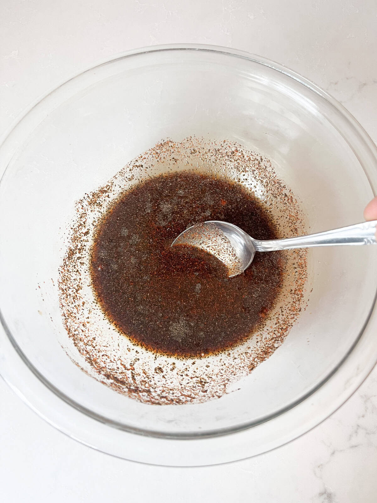 Mixing liquids and seasonings in a bowl with a spoon.
