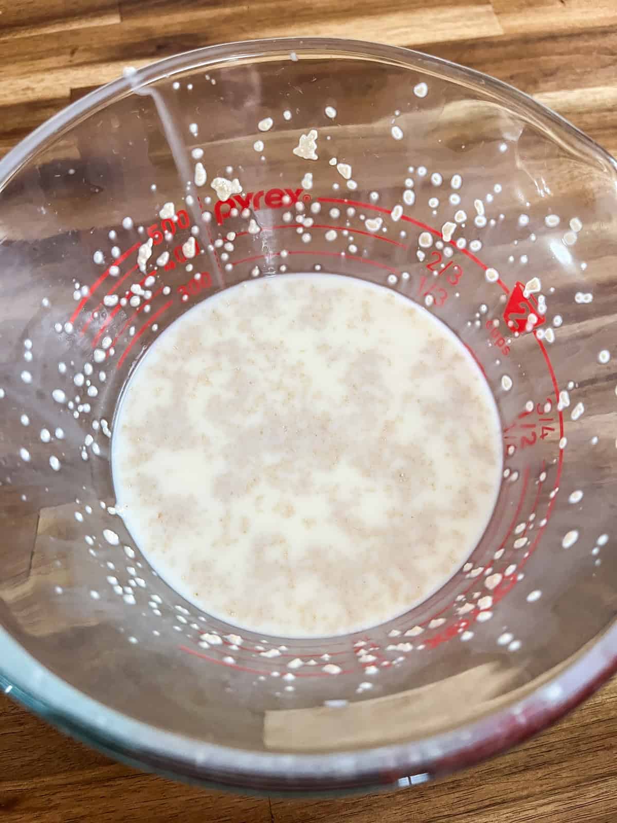 Blooming yeast in warm milk in a glass bowl.