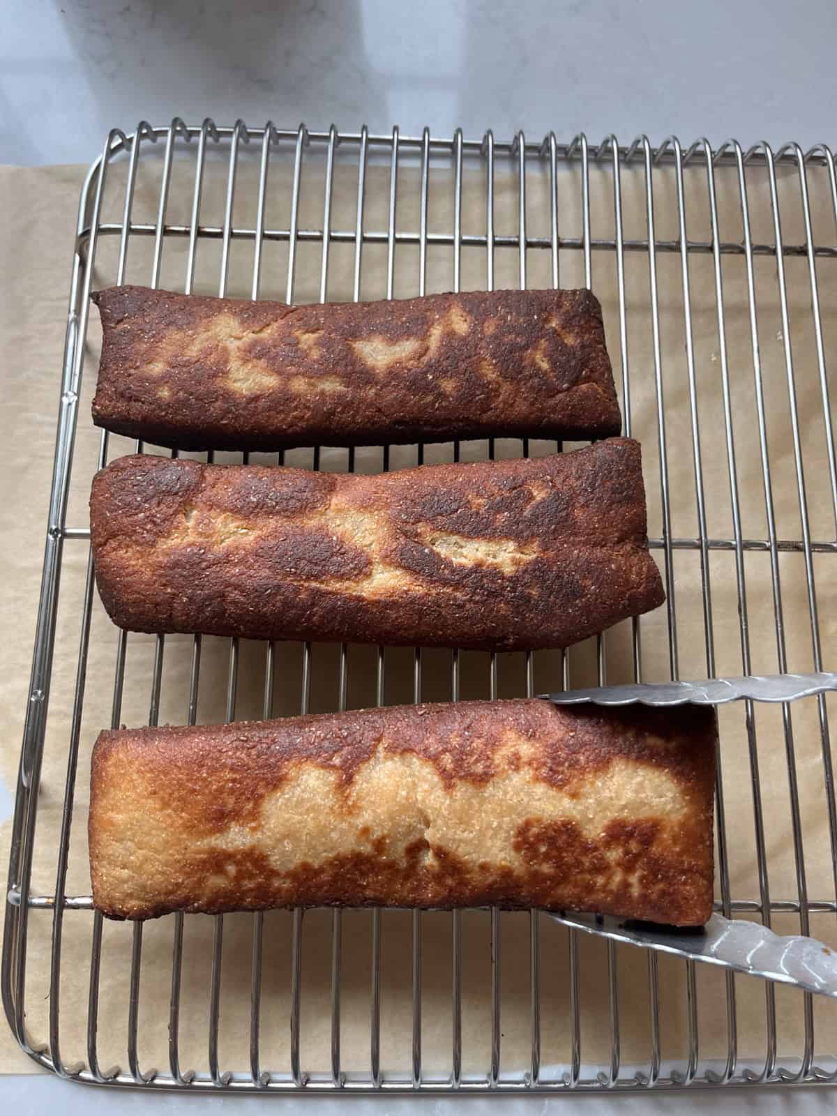 Fried maple bars on a cooling rack before glazing.
