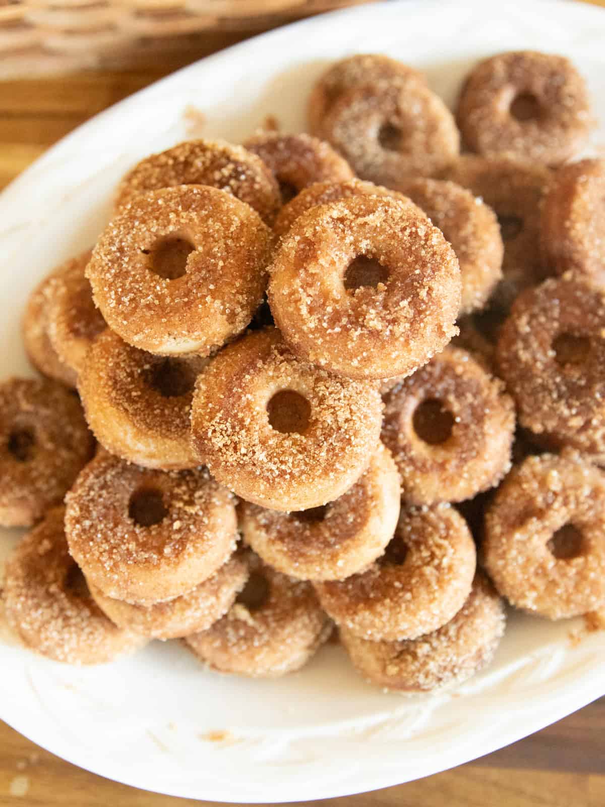 Looking down on a large white platter of apple cider donuts.