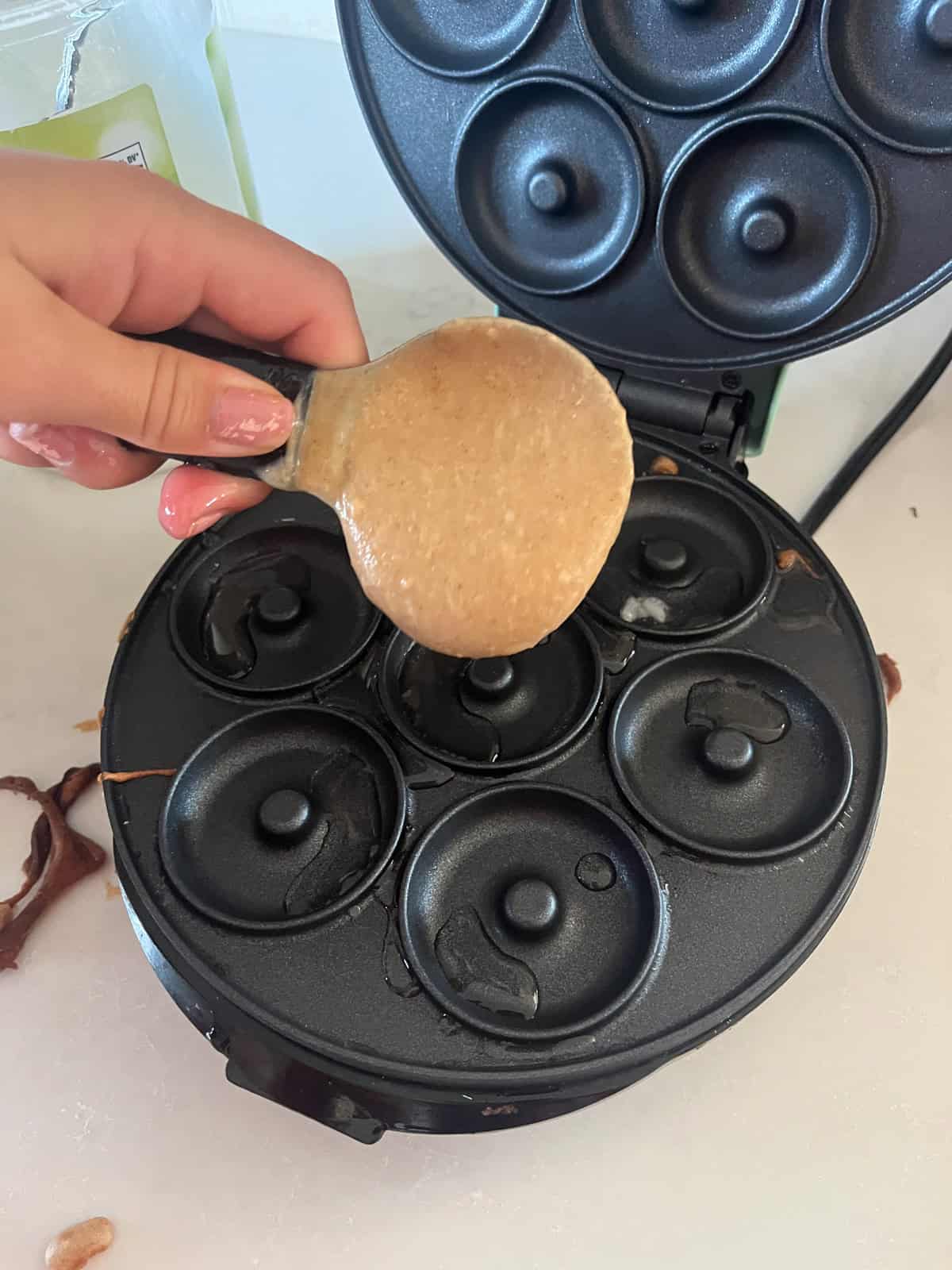 Pouring donut batter into a mini donut maker.
