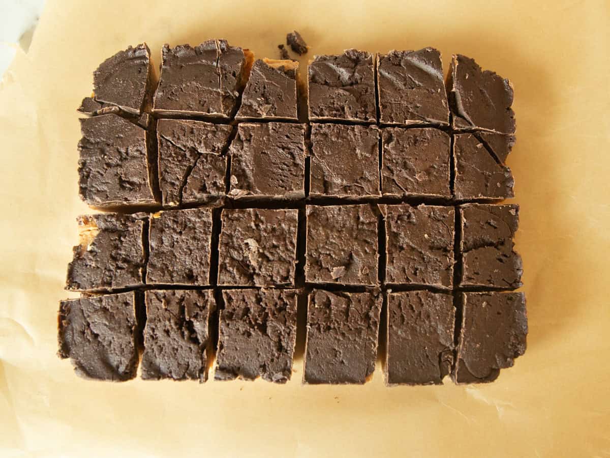 Chocolate peanut butter bars cut into squares on a wooden board.
