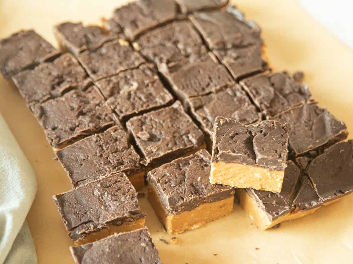 Peanut butter chocolate squares sitting on a wooden surface.