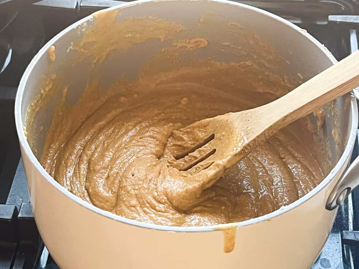 Stirring peanut butter mixture in a saucepan on the stove.