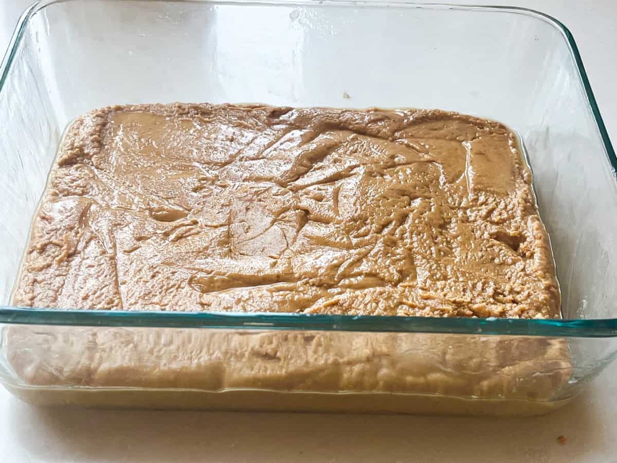 Peanut butter mixture pressed into a glass baking dish.