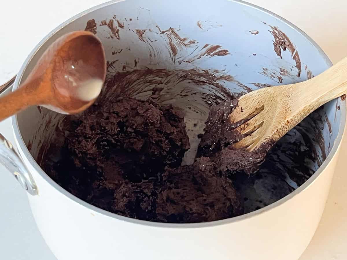 Pouring milk into a pan of melted chocolate.
