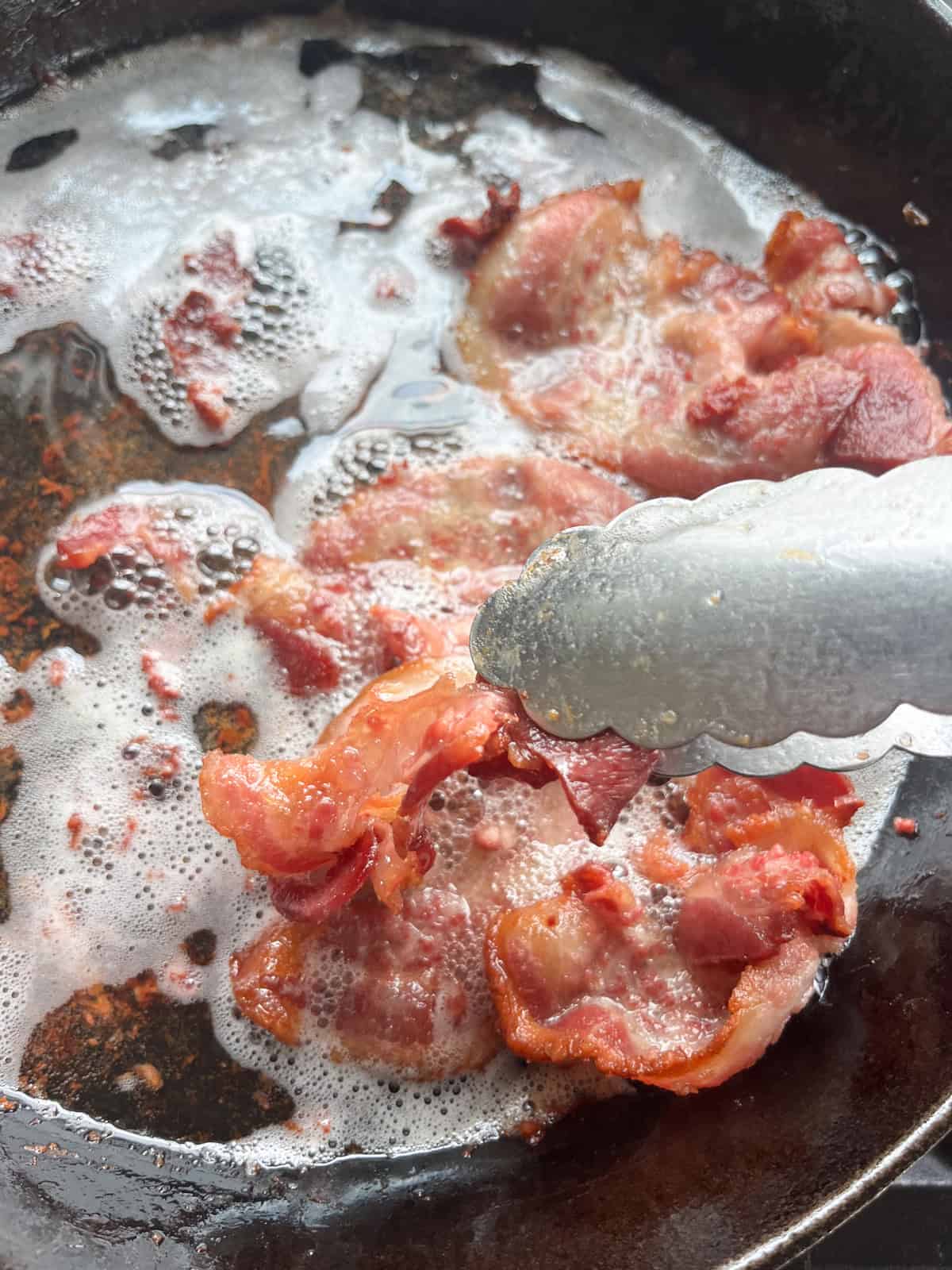Frying bacon in a cast iron skillet.