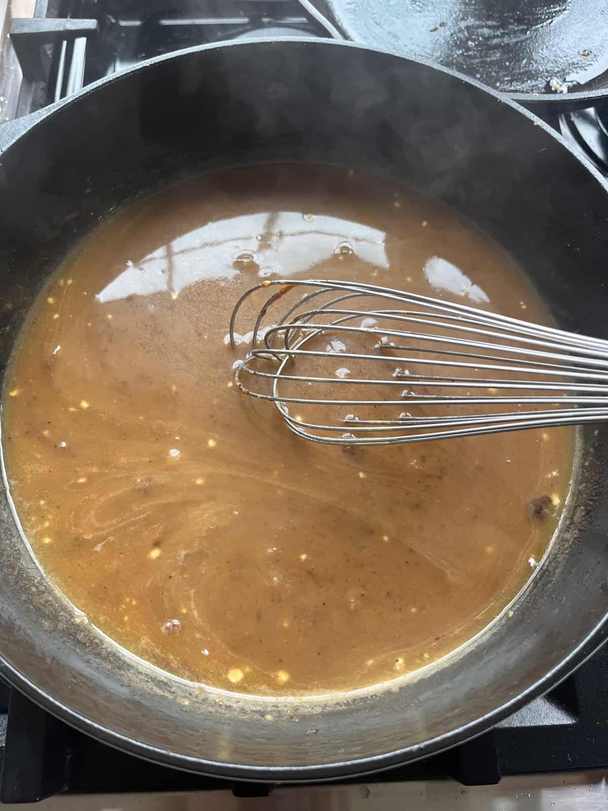 Whisking brown gravy in a cast iron skillet.