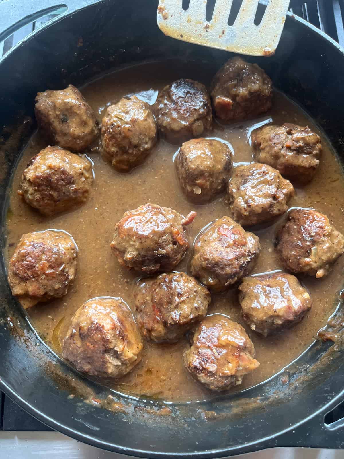 Meatballs and gravy in a cast iron skillet.