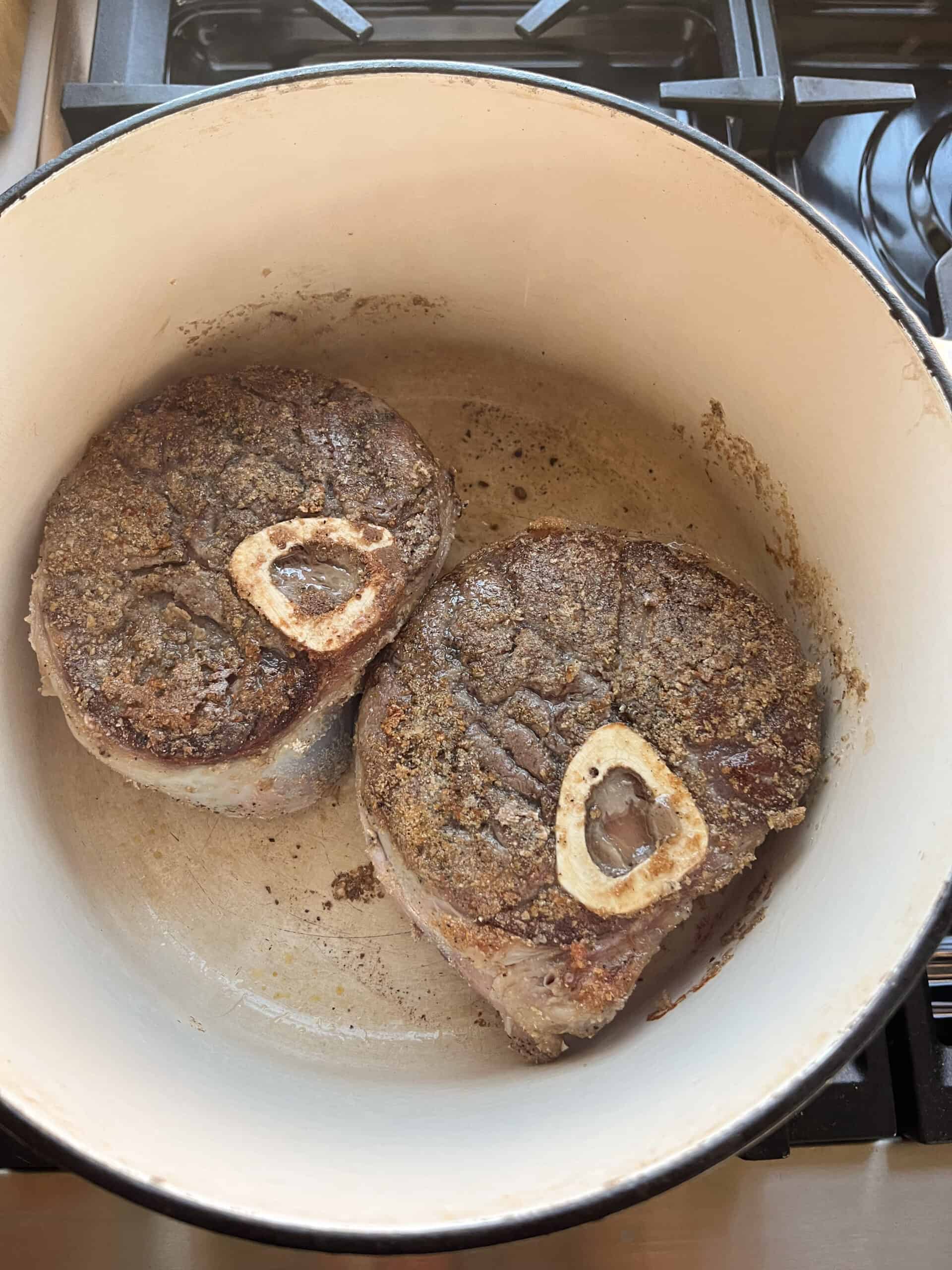 Searing beef shanks in a dutch oven.