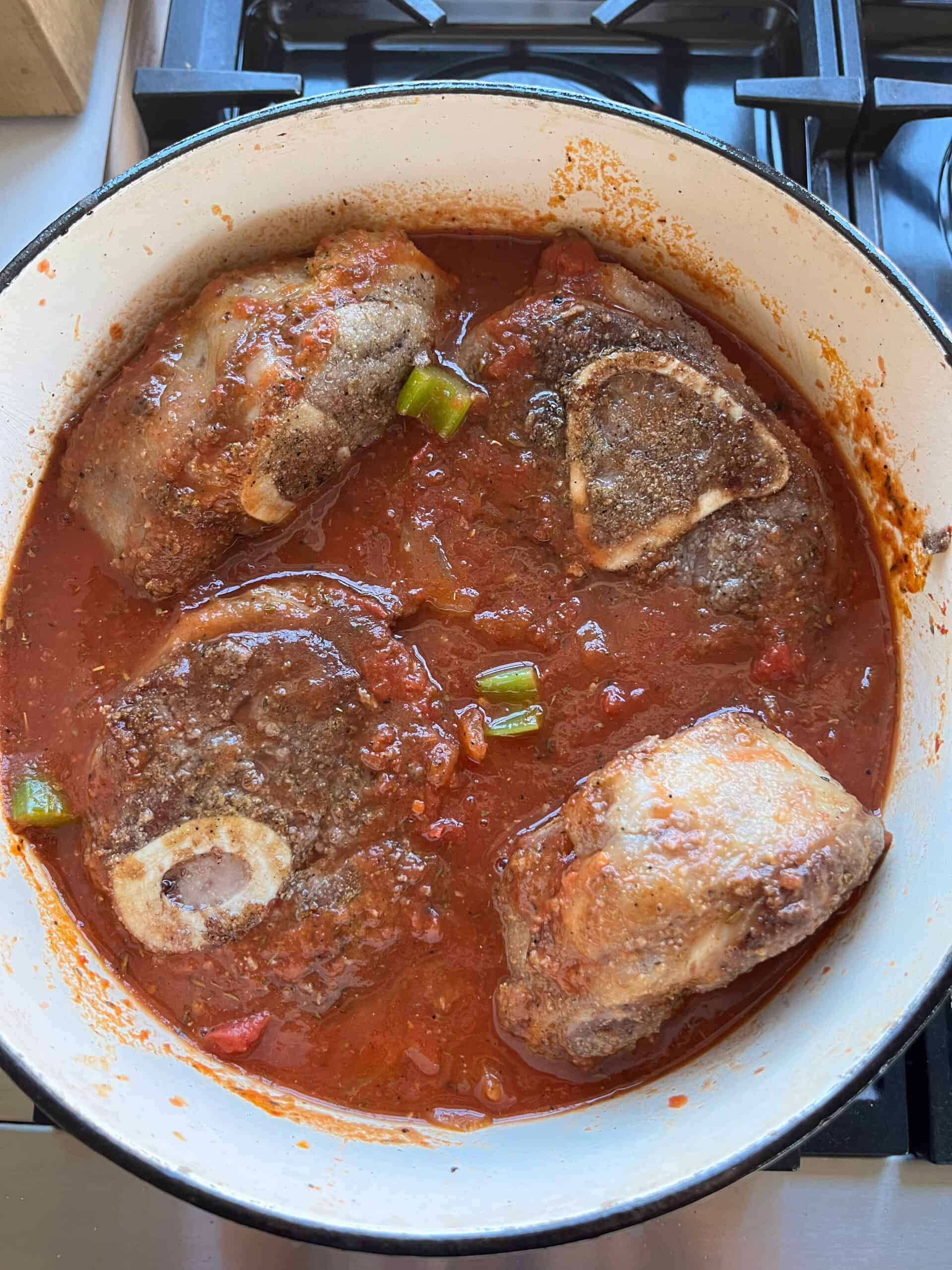Adding beef shanks back to the Dutch oven.