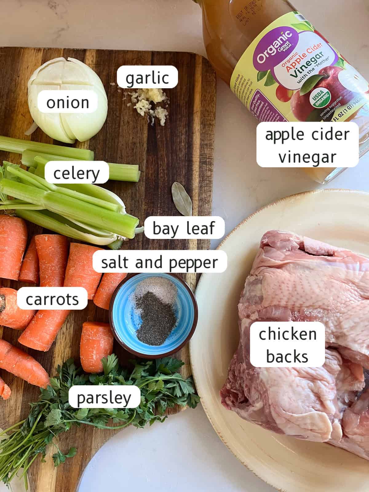 Dutch oven chicken broth ingredients labeled on a kitchen counter and cutting board.