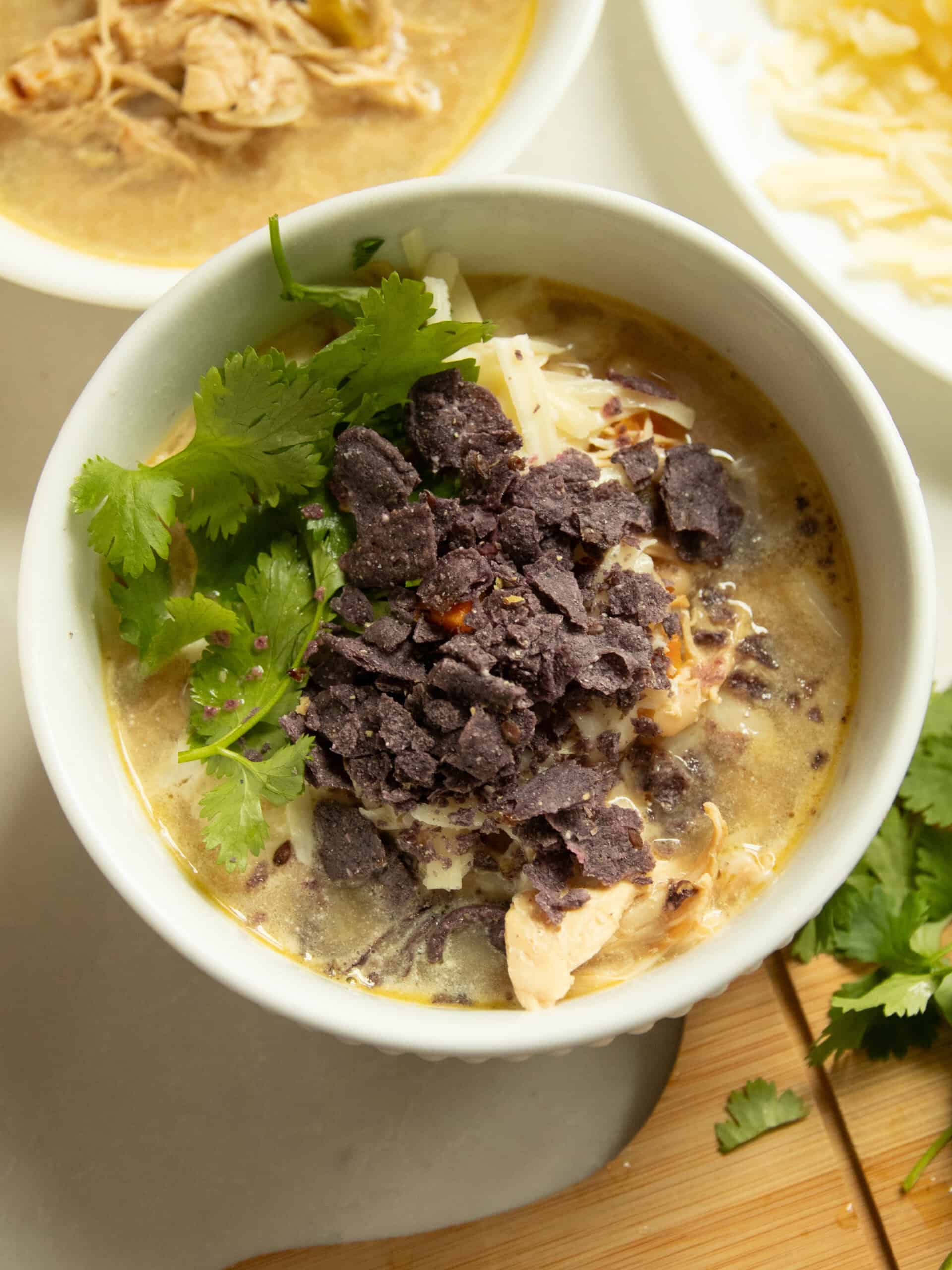 A bowl of white chicken chili with lots of toppings in it.