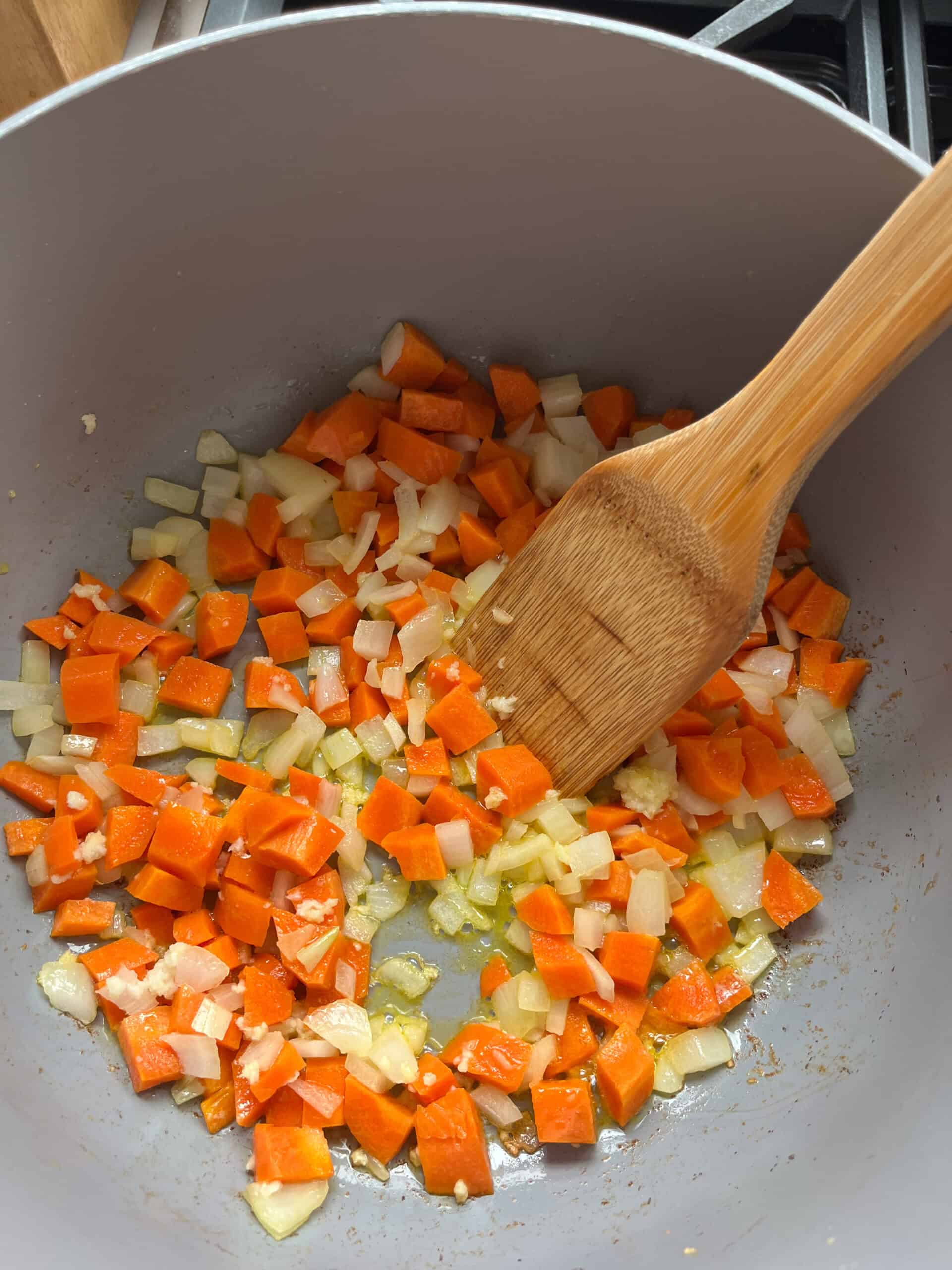Sauteing carrots and onion in a pot.