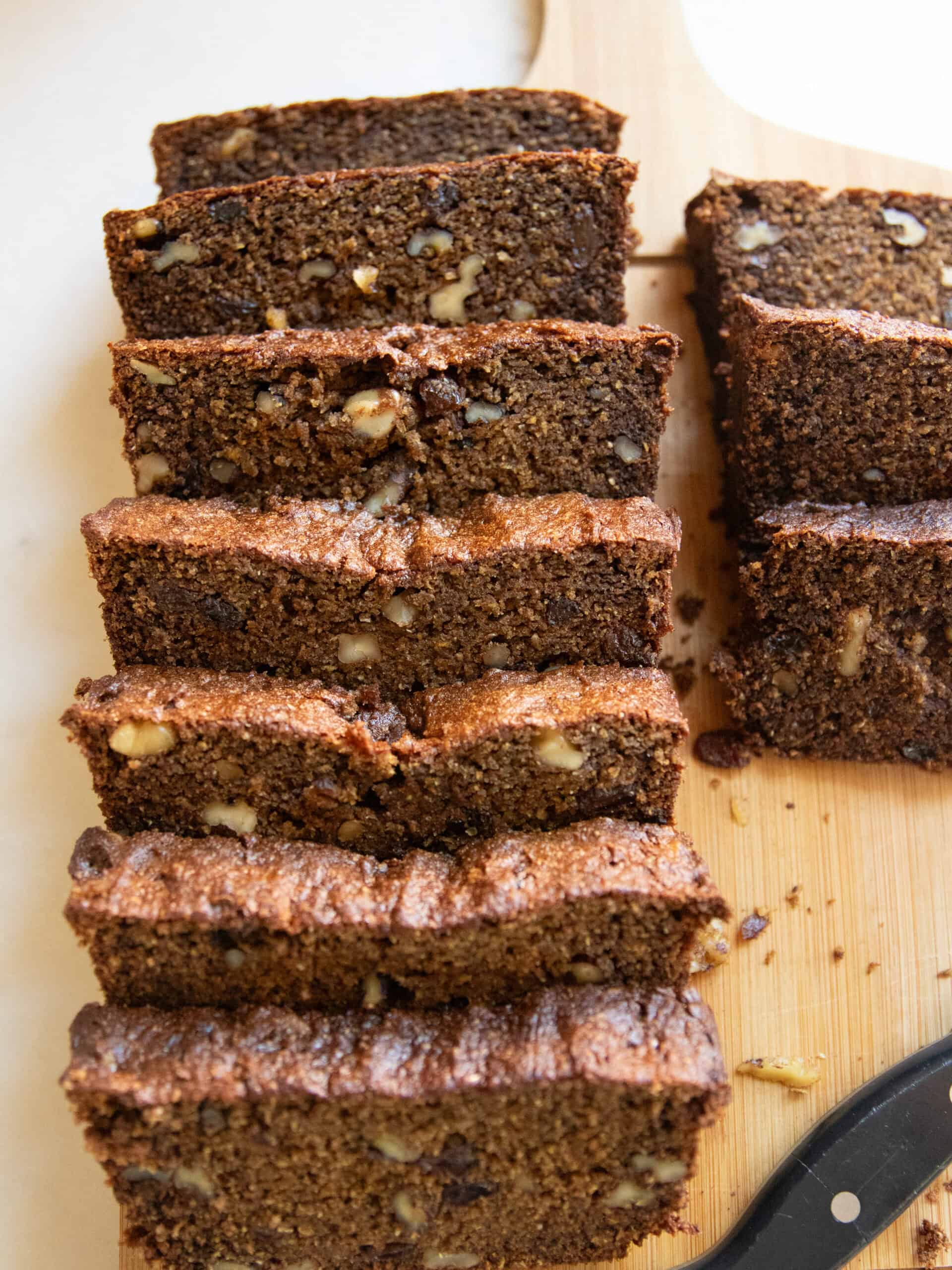Sliced persimmon bread stacked on a wooden board.