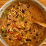 A pot of creamy chicken tortilla soup with a wooden ladel.
