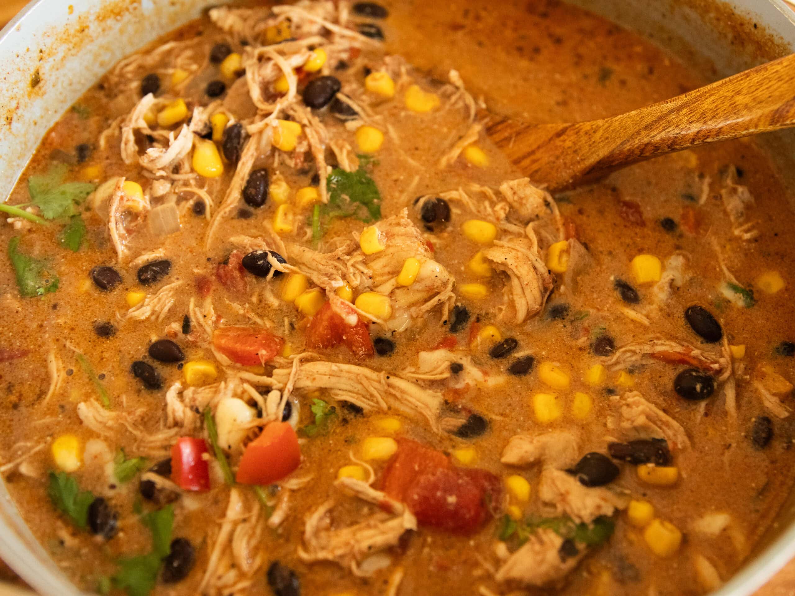A pot of creamy tortilla soup with a wooden ladel.