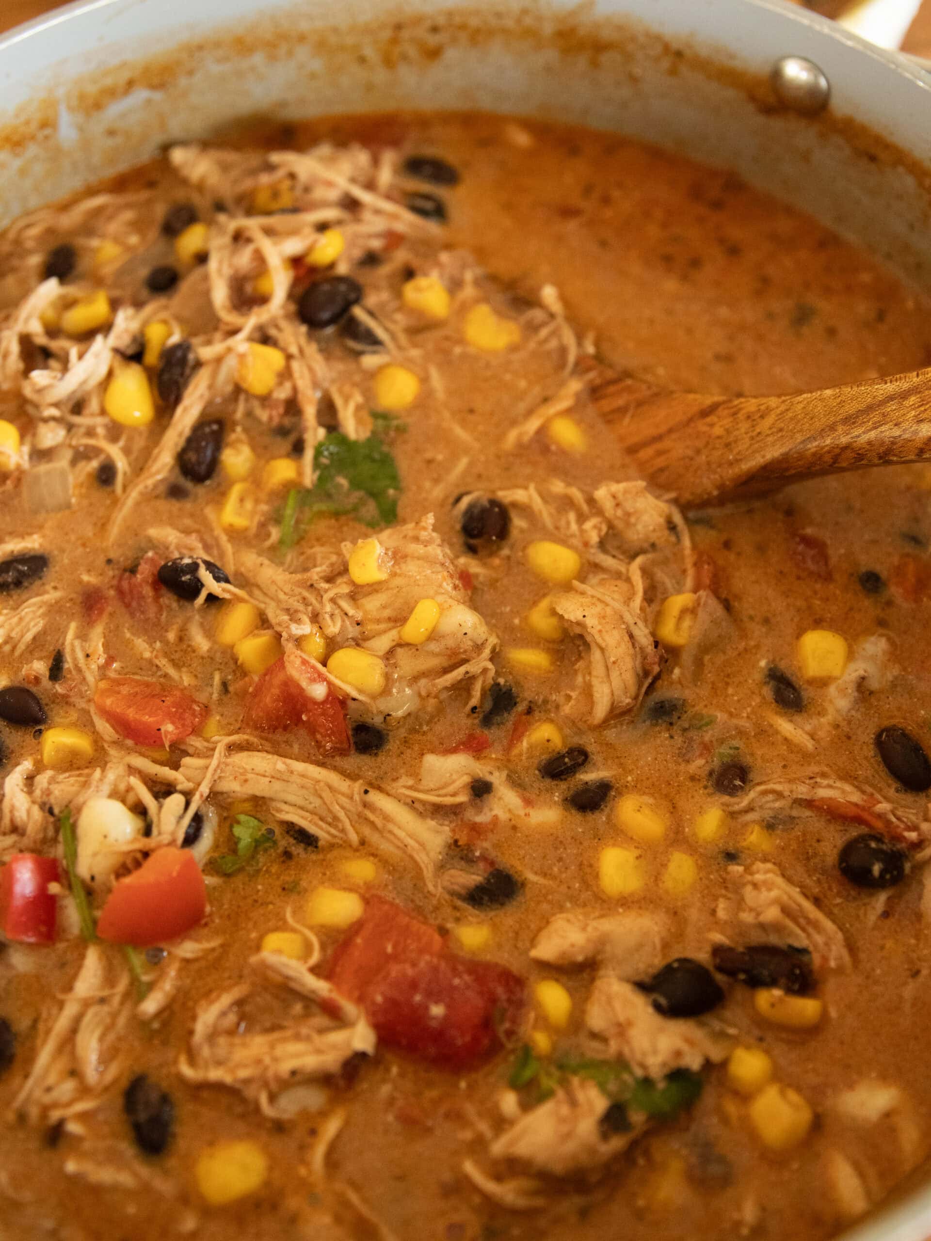 A pot of creamy chicken tortilla soup with a wooden ladel.