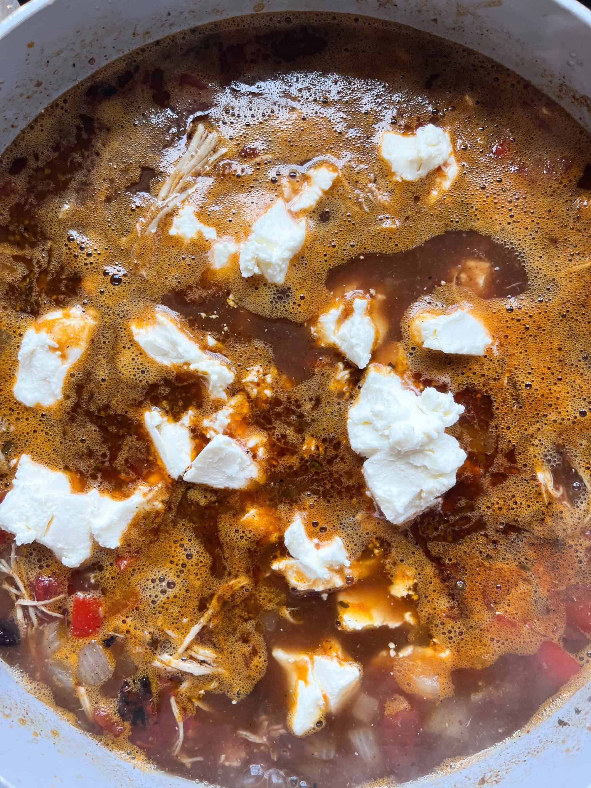 Adding cream cheese to the soup.
