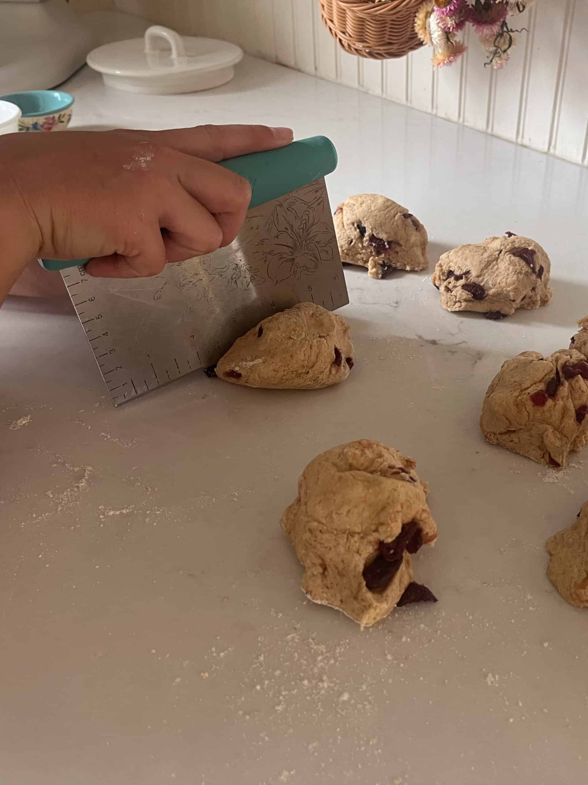 Cutting bagel dough into separate balls with a dough cutter.