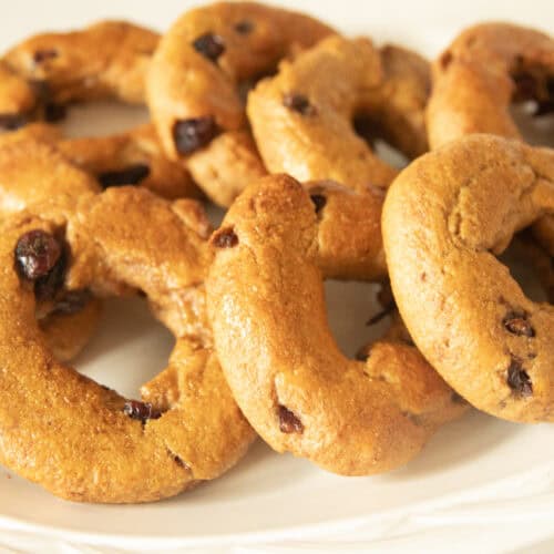 Cranberry bagels stacked on a white plate.