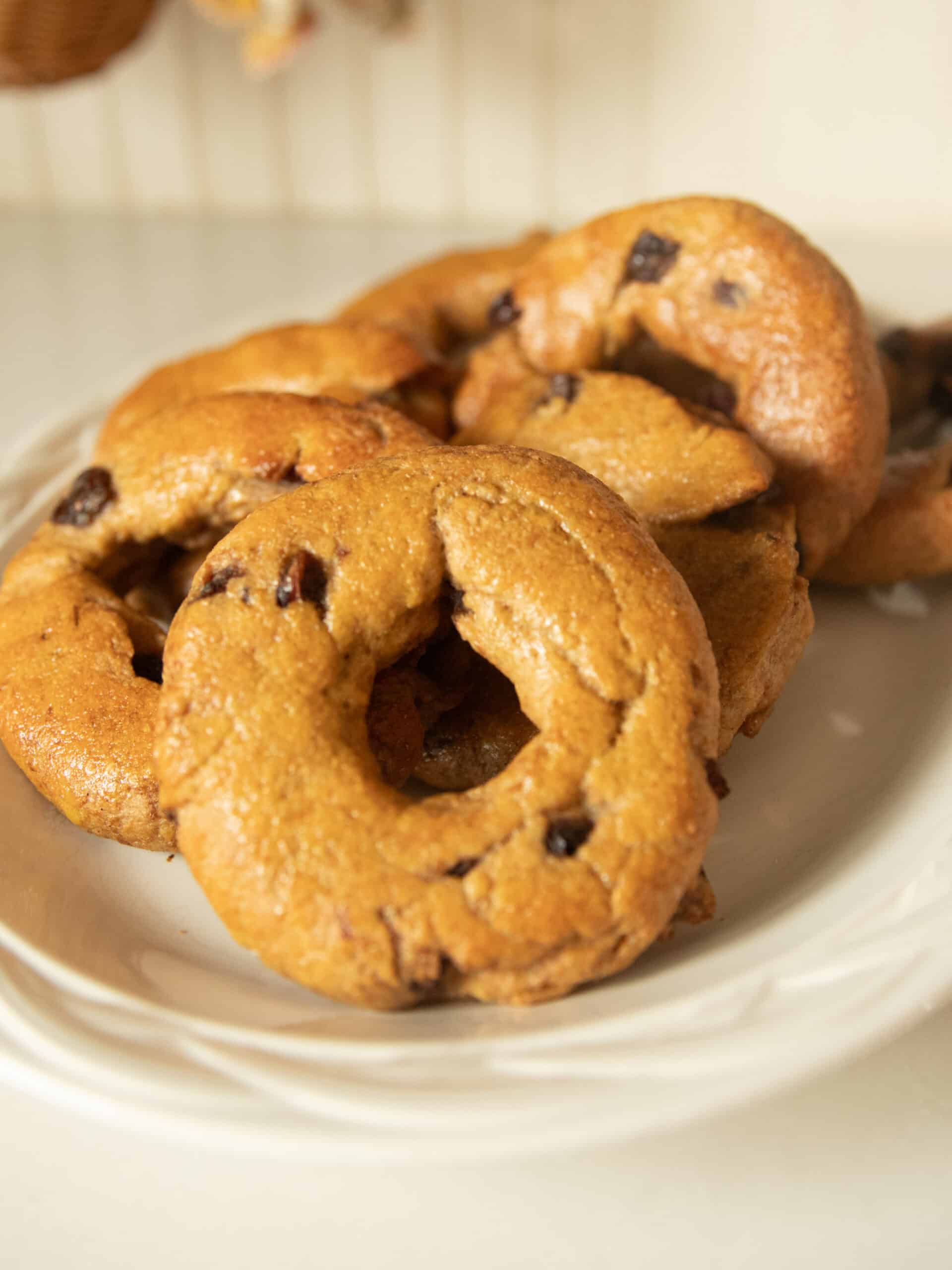 Whole wheat cranberry bagels stacked on a white plate.