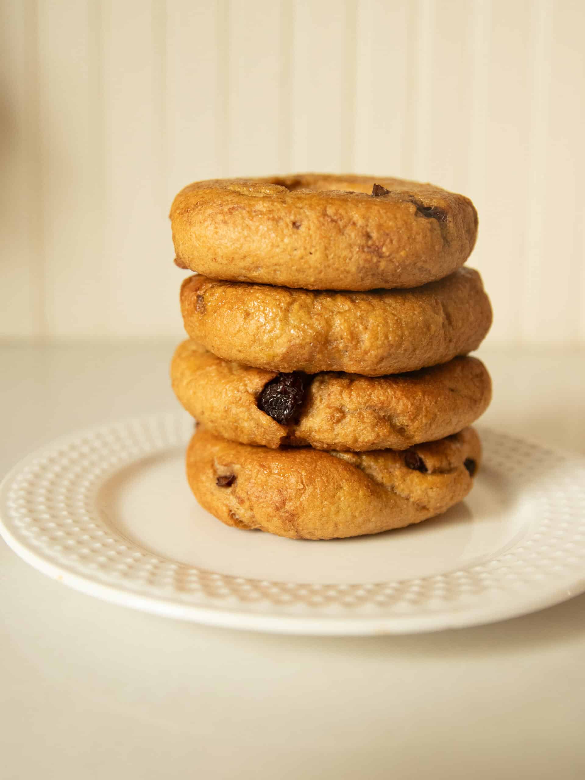 A neat stack of cranberry bagels on a white plate.