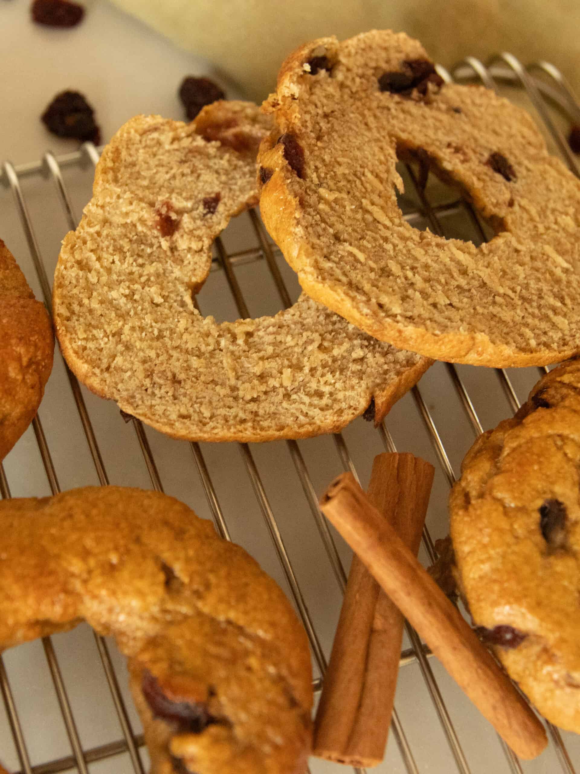 A sliced cranberry bagel on a cooling rack with whole backs.
